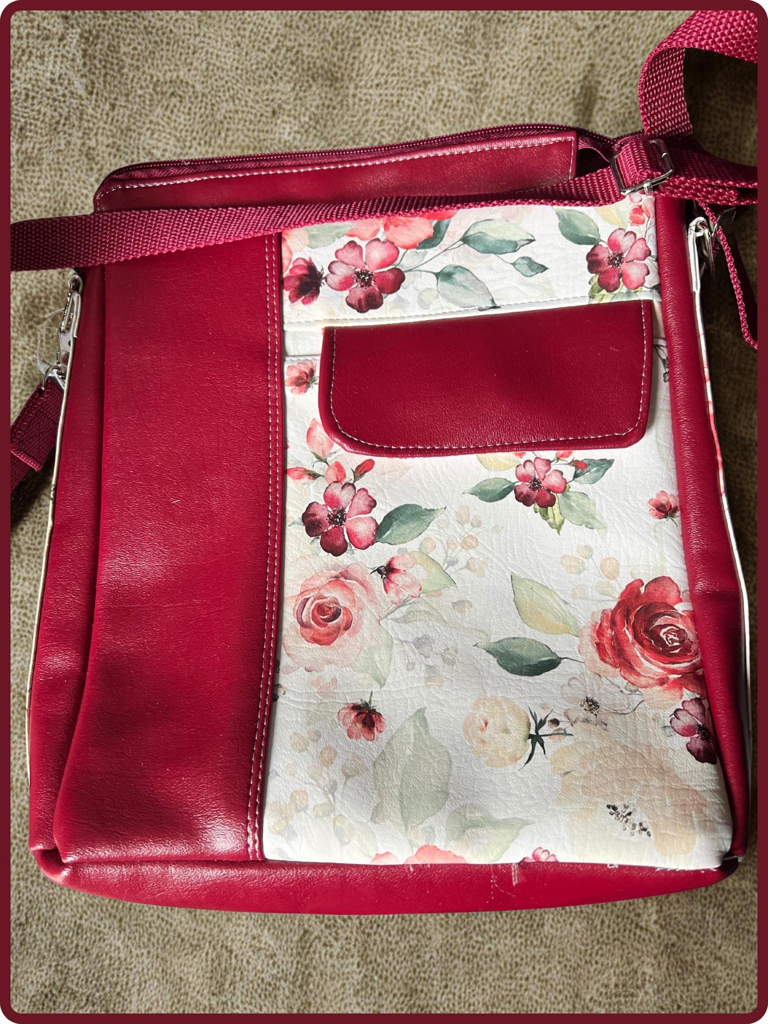 “Handmade red faux leather crossbody bag with adjustable strap and floral print front panel featuring watercolor roses and zippered top.